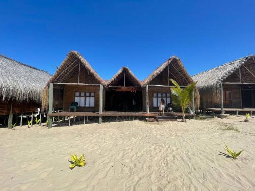 a row of huts on a beach with aermott at Cheerful 3-bedroom holiday beach cabin. in Inhambane