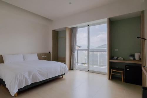 a bedroom with a white bed and a large window at Terumahouse 照間 民宿編號2016號 in Taitung City