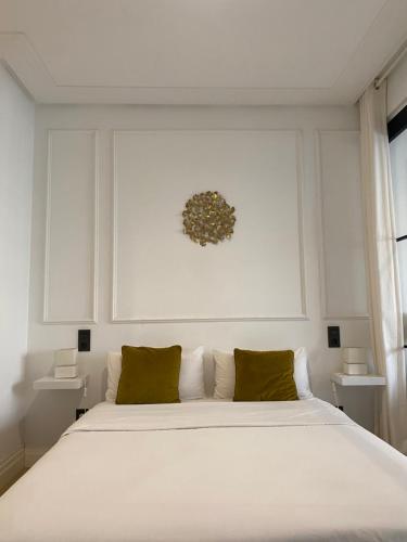una camera da letto con un grande letto bianco con cuscini verdi di Lujoso apto Paseo Del Prado a Madrid