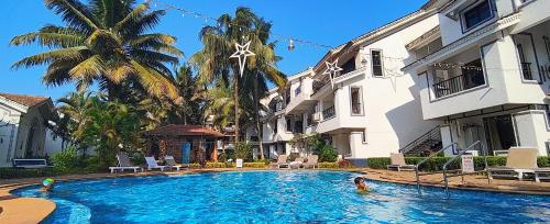 a swimming pool in front of a building with people in it at Susegad Suites Goa Apartments & Villas Riviera Hermitage Arpora in Arpora