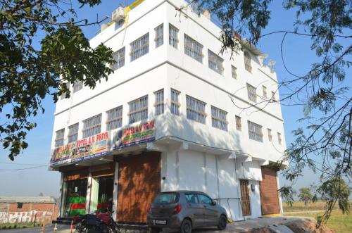 a white building with a car parked in front of it at Hotel AV Priya in Rājgīr