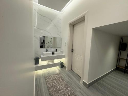Baño blanco con lavabo y espejo en شاليه الرتاج الفندقي en Buraidah
