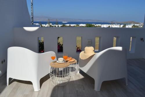 un balcone con 2 sedie e un tavolo con un cappello di White Nadora Naxos Villa ad Agia Anna Naxos