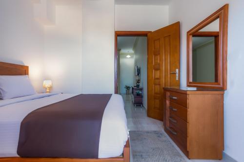 a bedroom with a bed and a dresser with a mirror at Lazur Sea & City Apartment's - El Hadaba, Hurghada - Egypt in Hurghada