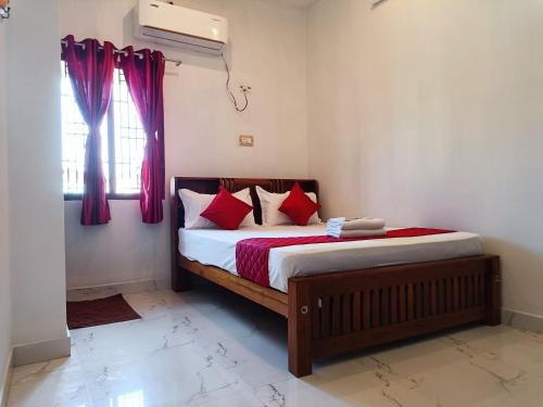 a bedroom with a bed with red pillows and a window at Rudra Villas in Rāmeswaram