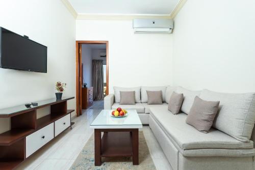 Lazur Hotel Apartments في الغردقة: غرفة معيشة مع أريكة بيضاء وطاولة