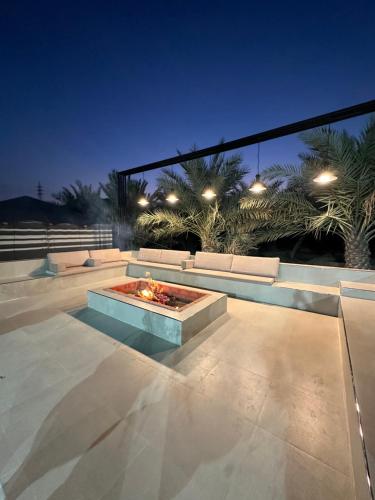 a patio with a fire pit at night at Algor Farm in Qūr