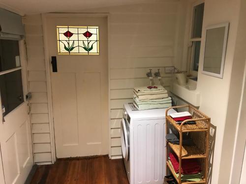 Melville Heritage Cottage, Hobart CBD في هوبارت: مطبخ صغير باللون الأبيض مع باب ونافذة