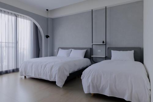 two beds in a room with white sheets at Terumahouse 照間 民宿編號2016號 in Taitung City