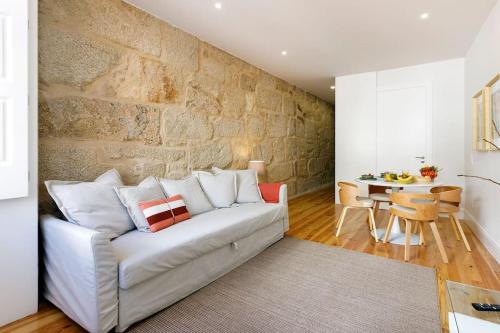 - un salon avec un canapé blanc et un mur en pierre dans l'établissement Oporto Cosy Apartment, à Porto