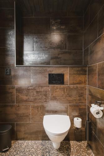 a bathroom with a white toilet and brown tiles at Jänkä Townhouse in Levi