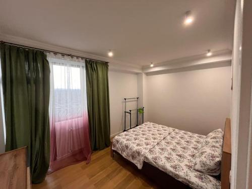 Schlafzimmer mit einem Bett und einem Fenster mit grünen Vorhängen in der Unterkunft Cosy Apartment in Varketili in Samgori
