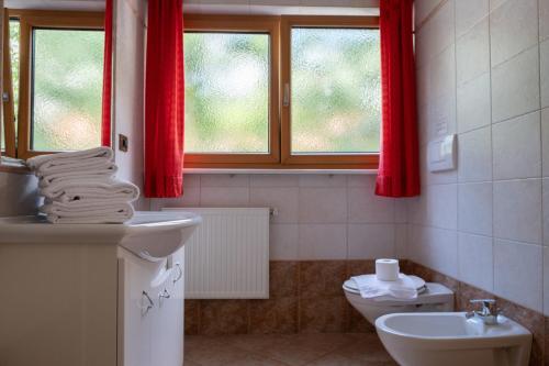 baño con lavabo, aseo y cortinas rojas en Ferienwohnung im Haus Texel II, en Rablà