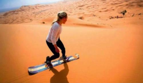 uma mulher andando no deserto segurando um cano em Sahara desert luxurious Camps em Merzouga