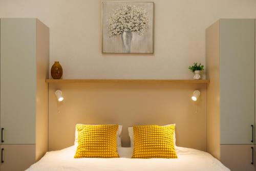 a bedroom with a bed with two yellow pillows at Victoriei Square Apartment in Timişoara