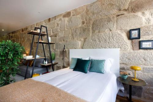 1 dormitorio con cama blanca y pared de piedra en Oporto Lovely Apartment, en Oporto
