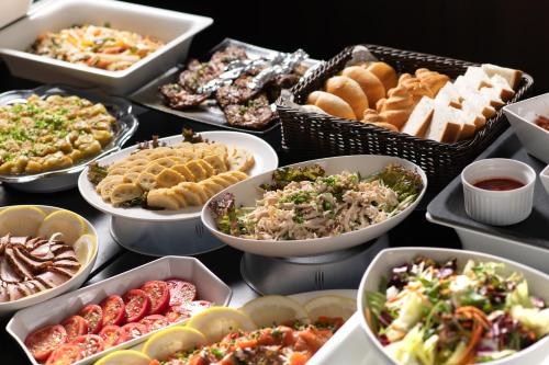 a table with many different types of food in bowls at Hotel Vista Kumamoto Airport in Ozu