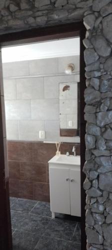 uma casa de banho com um lavatório e uma parede de pedra em Casa en el faro sona sur asta 5 plazas em Mar del Plata