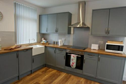 a kitchen with gray cabinets and a white sink at Seaglass Cottage - Redcar in Redcar