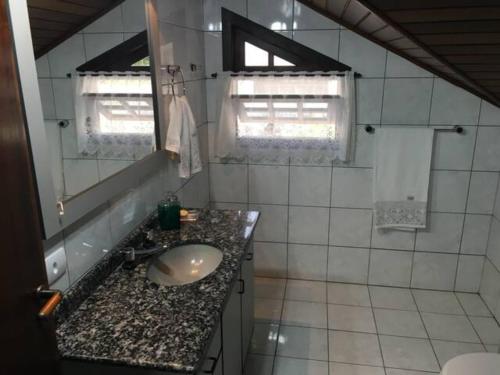 un baño con lavabo y espejo en Casa Leicht - Quarto Família, en Blumenau