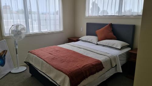 a bedroom with a bed and a fan and windows at El Beracca Retreat - A home away from home in Palmerston North