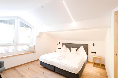 a white bedroom with a large bed and a window at Hotel Salzburger Hof in Dienten am Hochkönig