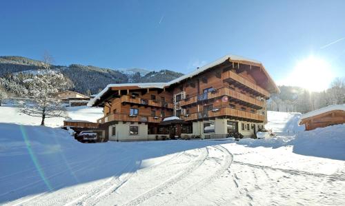 ein großes Gebäude im Schnee mit einer Straße davor in der Unterkunft Ski in Ski out Hotel Unterellmau in Saalbach-Hinterglemm