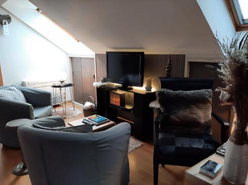 ein Wohnzimmer mit einem Sofa und einem TV in der Unterkunft Reve gourmand in Beauraing