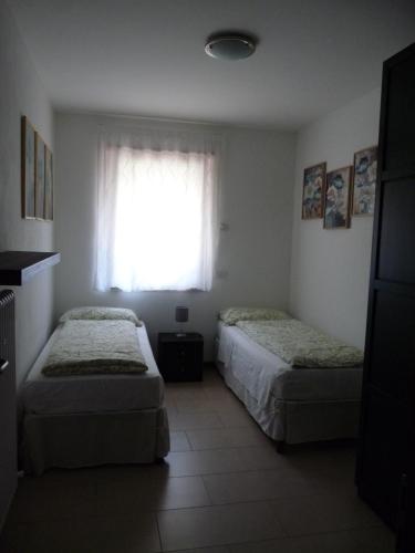 two beds in a room with a window at Appartamento Mora in Tenno
