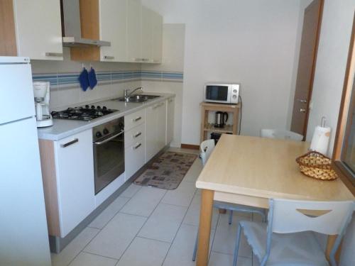 uma cozinha com armários brancos e uma mesa com um lavatório em Appartamento Mora em Tenno