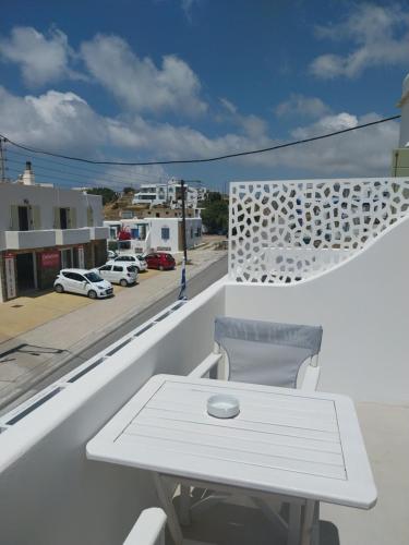 a white table and chair on a balcony with a street at Altana Boutique Hotel in Tinos Town