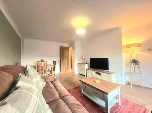 a living room with a couch and a tv at Comfortable Norfolk Bungalow in Dersingham