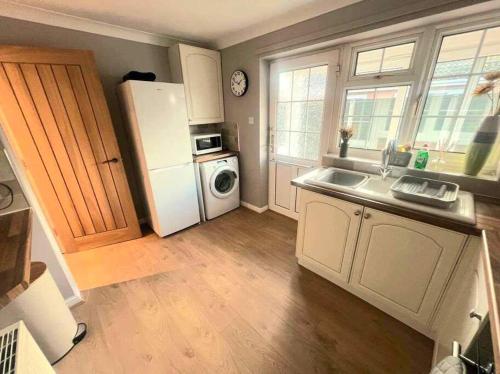 a kitchen with a white refrigerator and a washer and dryer at Comfortable Norfolk Bungalow in Dersingham