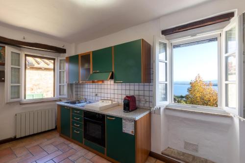 a kitchen with green cabinets and a large window at Il Torrione in Castiglione del Lago