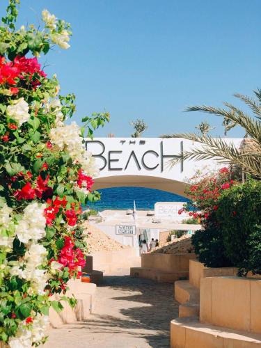 a beach sign with red and white flowers at Elisir SPA & Hotel at Sheikh coast in Sharm El Sheikh