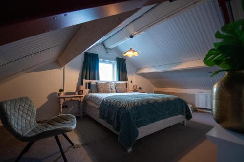 een slaapkamer op zolder met een bed en een stoel bij Sfeervol Appartement Het Knooppunt in Nuis