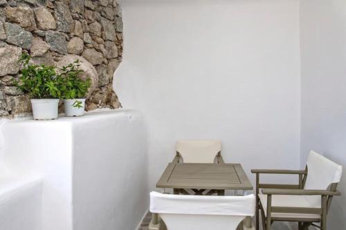 een tafel en stoelen voor een stenen muur bij Raffar luxury houses Psarou in Platis Yialos Mykonos