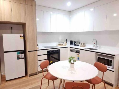 a kitchen with a white table and chairs in it at Gungahlin Center-1 Bedroom New Stylish Unit in Harrison