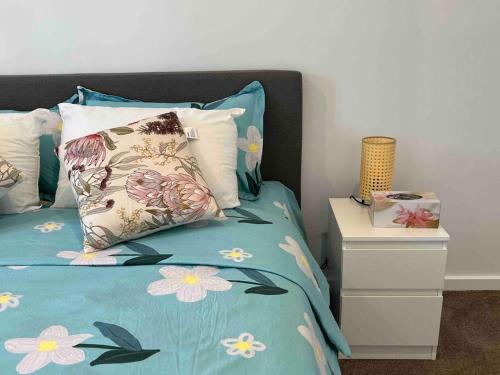 a bed with a blue comforter with flowers on it at Gungahlin Center-1 Bedroom New Stylish Unit in Harrison