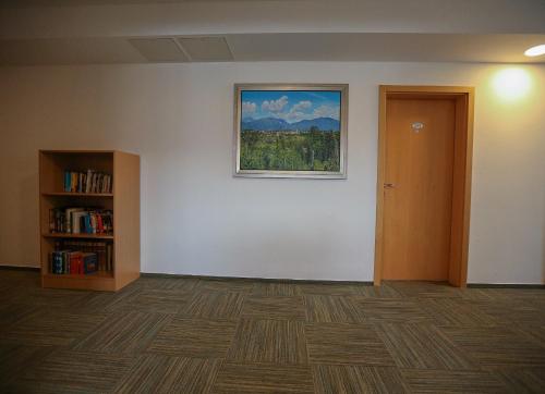 a room with a painting on the wall and a book shelf at Grajski Dvor in Radovljica