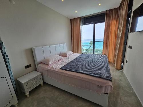 een slaapkamer met een bed en uitzicht op de oceaan bij Konak Tower Seaside in Alanya