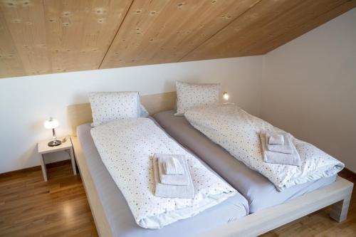 1 dormitorio con 2 camas con sábanas blancas en Chasa Bagnera 174, en Scuol