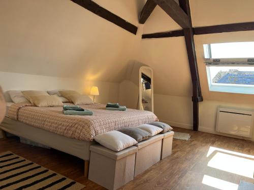 een slaapkamer met een bed met kussens erop bij Duplex Beauregard - calme & proche de la plage in Dieppe