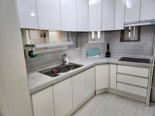 a kitchen with white cabinets and a sink at Suwon station City House in Suwon