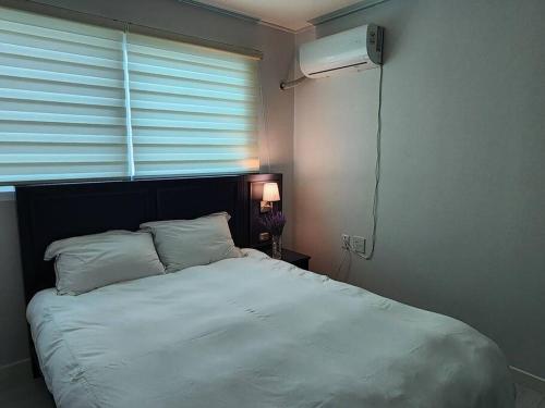a bedroom with a white bed and a window at Suwon station City House in Suwon