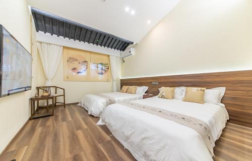 a hotel room with two beds and a television at Ho You Homestay in Shaoxing