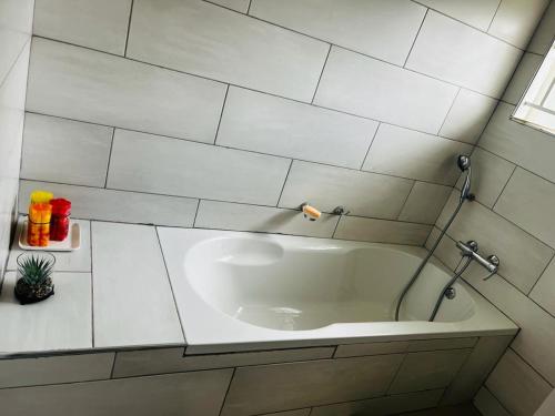 a bathroom with a sink in a white tiled wall at Elisheva apartment in Ndola