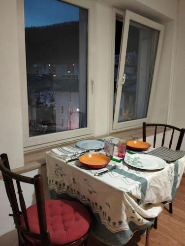 uma mesa com pratos e tigelas com uma janela em Appartement cosy et chaleureux em Morez