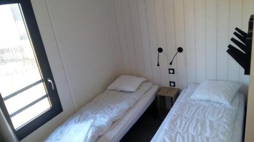 twee bedden in een kamer met een raam bij Cottage chalet gîte l'Edune résidence de vacances location in Jullouville-les-Pins