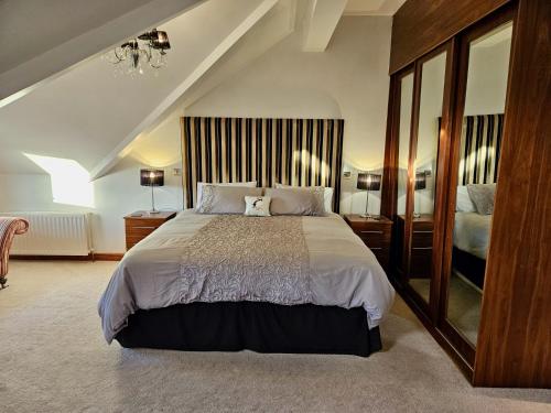 1 dormitorio con 1 cama grande y espejo grande en Atlantic View Coach House, en Portstewart